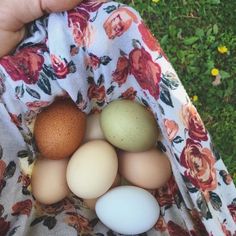 a person holding a bag with eggs in it and flowers on the fabric around them