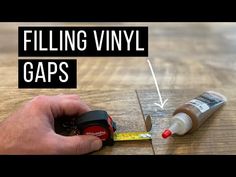 a person is filling vinyl gaps with glue on a wooden table and measuring tape