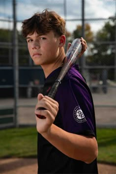 a young man holding a baseball bat on top of a field