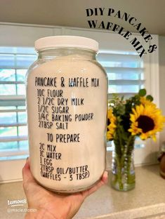 a person holding up a jar filled with homemade diy pancake waffle mix