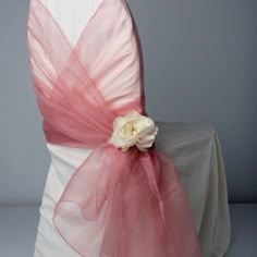 a chair with a pink sash on top of it and a white rose in the center