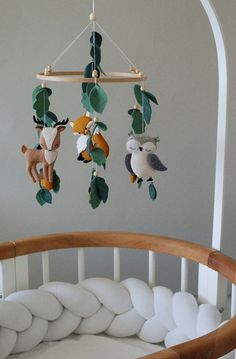 a baby crib with several stuffed animals hanging from it's sides and leaves