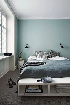 a bed sitting in a bedroom under a window next to a book shelf filled with books