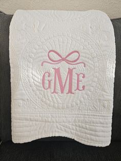 the monogrammed blanket has a pink bow on it and is sitting on a couch