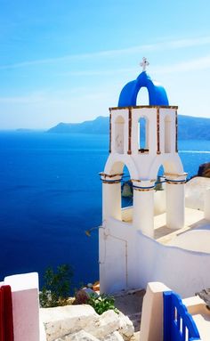 a white church with blue domes overlooking the ocean