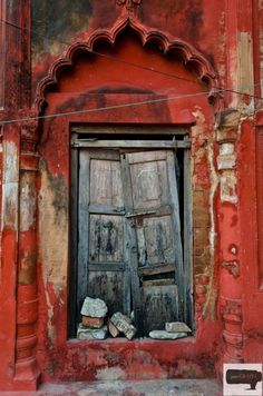 an old red building with a wooden door and window on the outside, in india