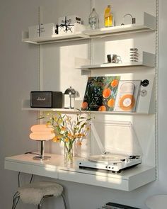 a white desk topped with a laptop computer next to a shelf filled with books and other items