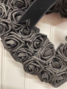 a heart shaped wreath made out of grey fabric with black ribbon hanging on the front door