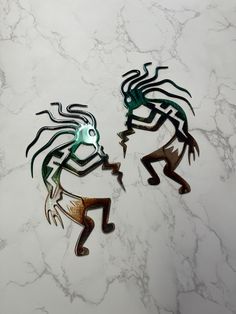 two metal horses on a marble surface with black and green designs in the shape of people