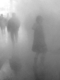 several people walking in the fog on a street