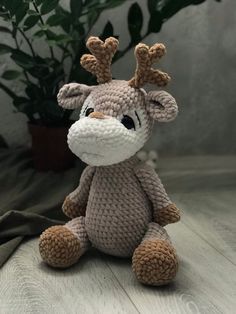 a crocheted stuffed animal sitting on top of a wooden table next to a potted plant