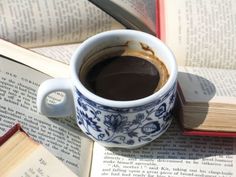 a cup of coffee sitting on top of an open book