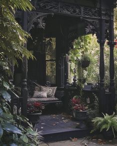 a black gazebo surrounded by greenery and potted plants