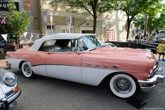 an old pink and white car parked on the street