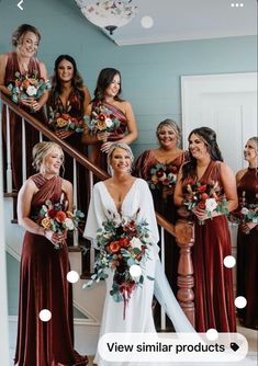 a group of women standing next to each other in front of a stair case holding bouquets