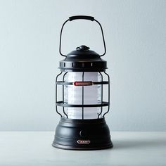 a black and white lantern sitting on top of a table next to a gray wall