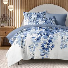 a bed with blue flowers on it in a room next to a night stand and nightstand