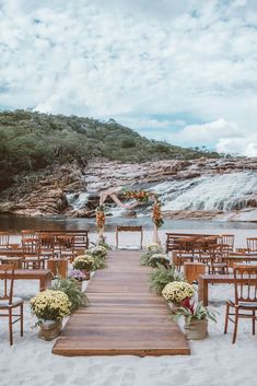 an outdoor ceremony set up with wooden chairs and flowers on the aisle, overlooking a waterfall