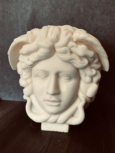 a white sculpture of a woman's head on a table