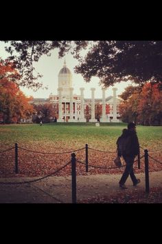 a person walking down a sidewalk in front of a building with a dome on top