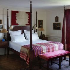 a bedroom with four poster bed and red curtains