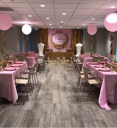 a banquet room set up for a party with pink and gold decorations on the walls