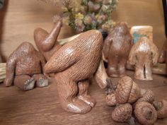 some little figurines sitting on top of a wooden table next to pine cones