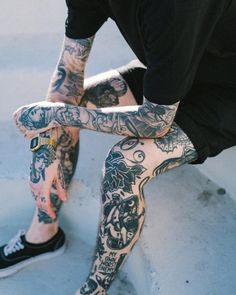 a man with tattoos on his legs sitting down