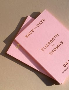 two pink save the date cards sitting on top of each other