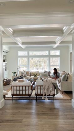 a woman sitting on top of a couch in a living room next to a window