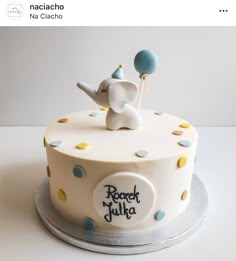 a white cake with an elephant on top and balloons in the shape of a balloon