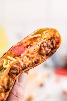 a hand holding a half eaten sandwich with meat and cheese