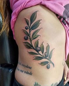 a woman's stomach with an olive branch tattoo on her side and words written below it