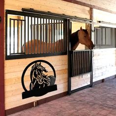 a brown horse sticking its head out of a stable door with black bars on it