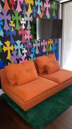 an orange couch sitting in front of a colorful wall