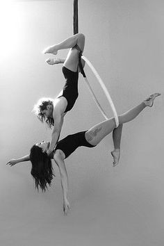 two women are performing aerial acrobatic tricks