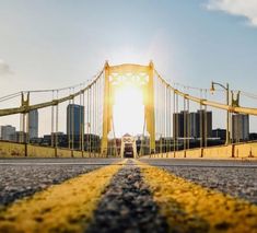 the sun shines brightly through the bridge as it crosses over an asphalt road in front of tall buildings