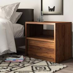 a bedroom with a bed, nightstand and mirror on top of the dresser next to it