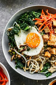 a bowl filled with rice, carrots and tofu topped with an egg on top