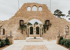 an old brick building with arched windows and arches on the front door is surrounded by greenery