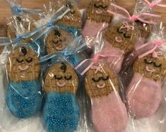 some cookies are wrapped in plastic bags and have been decorated with pink and blue icing