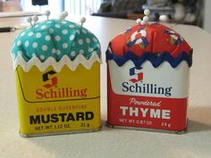 two tin canisters sitting on top of a table next to eachother