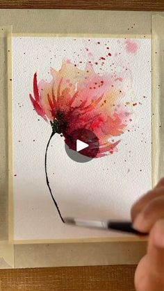 someone is painting a flower with watercolors