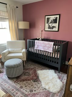 a baby's room with a crib, chair and ottoman in the corner