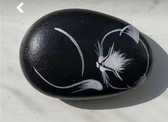 a black rock with white flowers painted on it