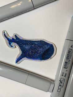 a blue whale sticker sitting on top of a white table next to a marker