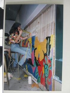 a man sitting on top of a chair next to a wall covered in colorful art