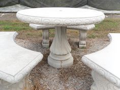 two cement benches sitting next to each other on top of gravel covered ground in front of a fence