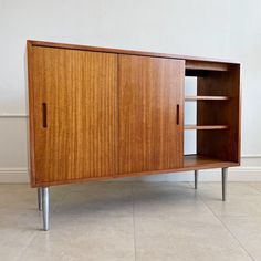 a wooden cabinet sitting on top of a tile floor next to a wall with white walls