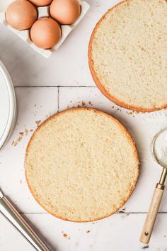 two cakes sitting on top of a white counter next to an egg and measuring spoon